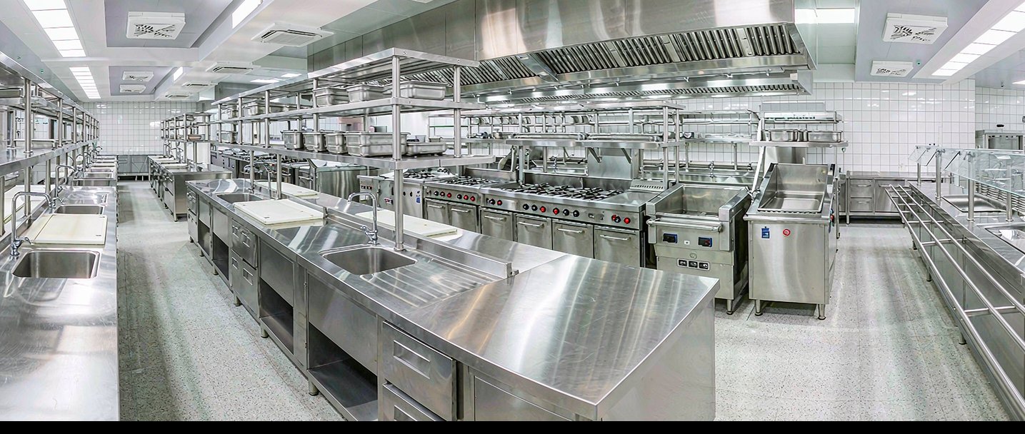 School kitchen with stainless steel worktables, gas ranges and exhaust hoods
